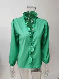 Dettaglio di una camicetta verde a maniche lunghe con eleganti volant lungo lo scollo a V.