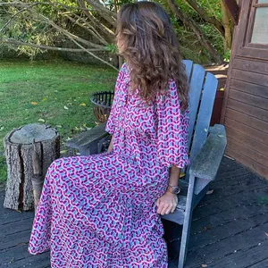 Detailansicht eines lila geometrischen Maxikleids mit Puffärmeln in einem Garten.