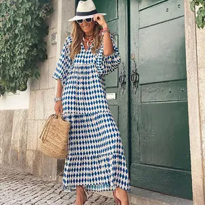 Frau im blauen Maxikleid mit geometrischem Rautenmuster, Puffärmeln und Stroh-Accessoires