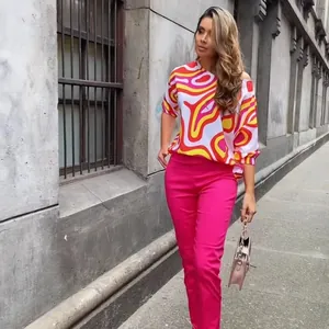 Detail view of woman wearing colorful geometric print blouse and hot pink trousers in street