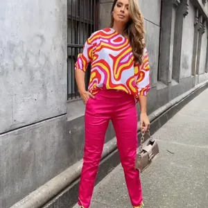 Woman wearing vibrant geometric print long-sleeved top and pink pants in street style