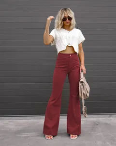 Stylish model in burgundy high-waisted corduroy flared pants standing outdoors.