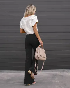 Detail view of black high waist corduroy flare trousers styled with a white knit top