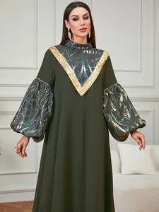 Elegant dark green long-sleeved gown featuring gold foil patterns and sequin trim details