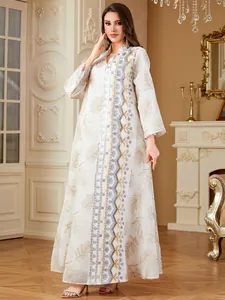 Detailopname van de elegante witte abaya met verfijnd goud en paars borduurwerk.
