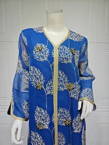 Detailed view of blue mesh embroidered dress with handmade beading and gold trim.