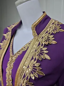 Detailaufnahme eines lila Kleides mit aufwendiger goldener Paillettenstickerei und Borten.