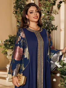 Detail of navy blue Abaya dress with floral sequin embroidery and gold clutch bag