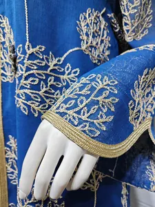 Macro view of gold embroidery and handmade beadwork on a blue mesh dress sleeve
