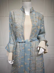 Dettaglio macro dell'elegante ricamo floreale azzurro sul cardigan con maniche a campana
