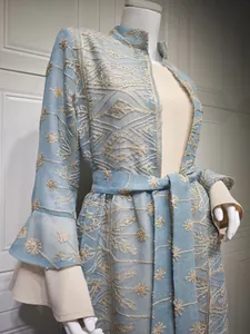 Elegante cardigan lungo azzurro con ricami floreali beige e maniche a campana.