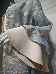 Primo piano di eleganti ricami floreali e maniche a campana su un set di cardigan blu.