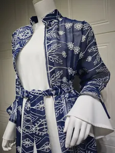 Dettaglio ravvicinato dell'elegante cardigan lungo ricamato blu con abito bianco a campana.