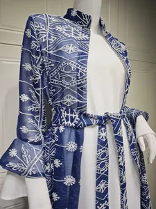 Dettaglio di elegante cardigan ricamato blu navy con maniche a campana su abito bianco