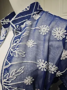Dettaglio dell'elegante ricamo floreale bianco su un abito di chiffon blu semitrasparente