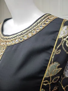 Close-up of black elegant dress featuring gold sequin embroidery and intricate detailing.