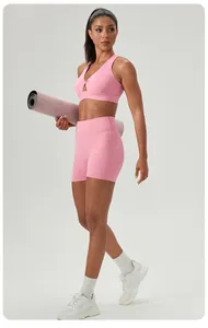 Full-body view of a model wearing a pink twisted sports bra and high-waisted yoga shorts