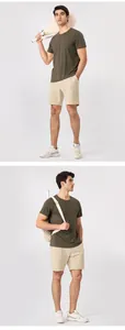 Modelo masculino vistiendo pantalones cortos deportivos beige en un estudio minimalista.