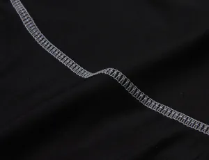 Detail shot of grey flatlock stitching on black moisture-wicking sports leggings fabric