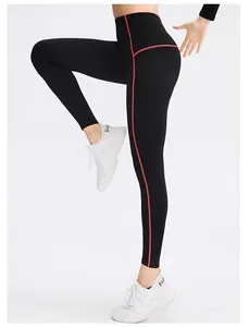 Close-up detail of black yoga leggings showing high-waisted fit and red contrast stitching