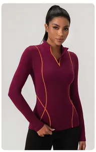 Nauwsluitende bordeauxrode sporttop met halve rits en opvallende oranje stiksels.