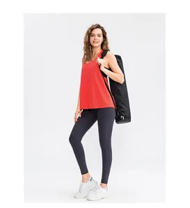 Vrouw in rode yoga tanktop en donkere legging met een yogamattas in een studio-opname