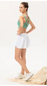 Mujer con falda pantalón blanca y sujetador deportivo verde para tenis, yoga o baile