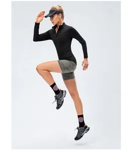 Fit woman running in black fleece-lined athletic long sleeve top and grey shorts.