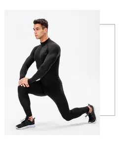 Heren thermische sportset zwart, model voert een lunge stretch uit voor fitnesstraining.