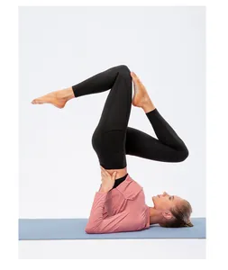 Femme en t-shirt de yoga rose à manches longues UPF50+ faisant du yoga sur un tapis