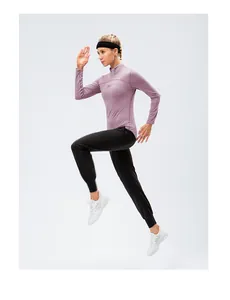Athletic woman jumping in a purple half-zip fitness top paired with black joggers