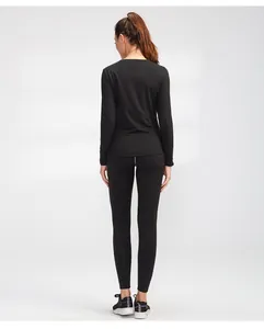 Rückansicht einer Frau im schwarzen Langarm-Yoga-Set mit Thermo-Leggings für Fitness.