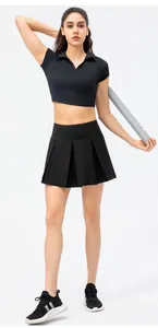 Full-body view of a professional women's black pleated tennis skirt and polo crop top set.