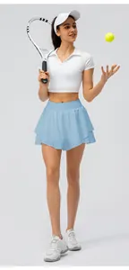 Vue en pied d'une femme portant une jupe-short de sport bleu clair avec une raquette