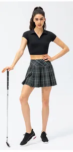 Woman in black crop polo and grey plaid pleated tennis skirt with golf club