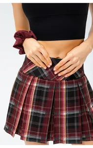 Detail of red and black plaid pleated sports skirt showing the high-waisted design.