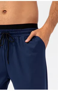 Detailopname van een donkerblauwe heren sportbroek met elastische taille en zakken.