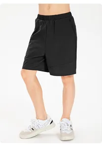 Detail view of black quick-dry children's athletic shorts on a model with white sneakers