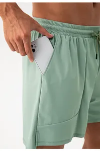 Detail view of men's sage green sports shorts showing large side pocket holding a phone