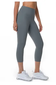 Detail view of gray high-waisted cropped yoga leggings on female model wearing sneakers