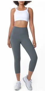 Detail of high-waist charcoal gray yoga leggings on model wearing white sports bra