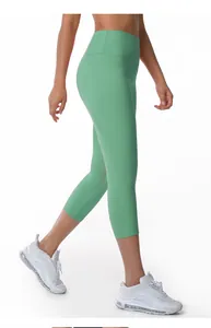 Side view of high-waisted green cropped yoga leggings on model with white sneakers