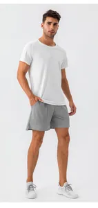 Model showcase of the loose fit and lightweight fabric of gray men's sports shorts.