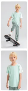 Young boy in a breathable light green color-block sports T-shirt with a skateboard.