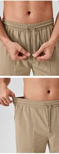 Detail view of men's khaki sports pants showing elastic waist and drawstrings.