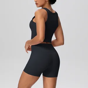 Zijaanzicht van een vrouw in een zwarte tweedelige yogaset met crop top en korte broek