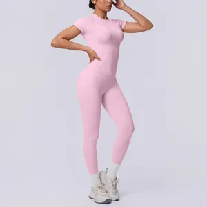 Seitenansicht einer Frau im rosa nahtlosen Yoga-Set mit Kurzarm und Leggings