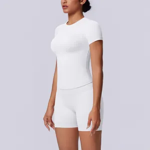 Zijaanzicht van een vrouw in een witte naadloze yoga-top met korte mouwen en bijpassende short