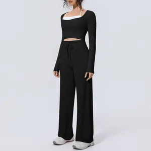 Model wearing black two-piece yoga set with long sleeve crop top and wide-leg pants