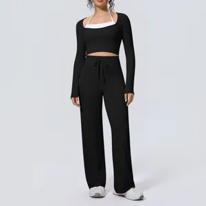 Front view of women's black yoga set with long sleeve crop top and wide-leg pants